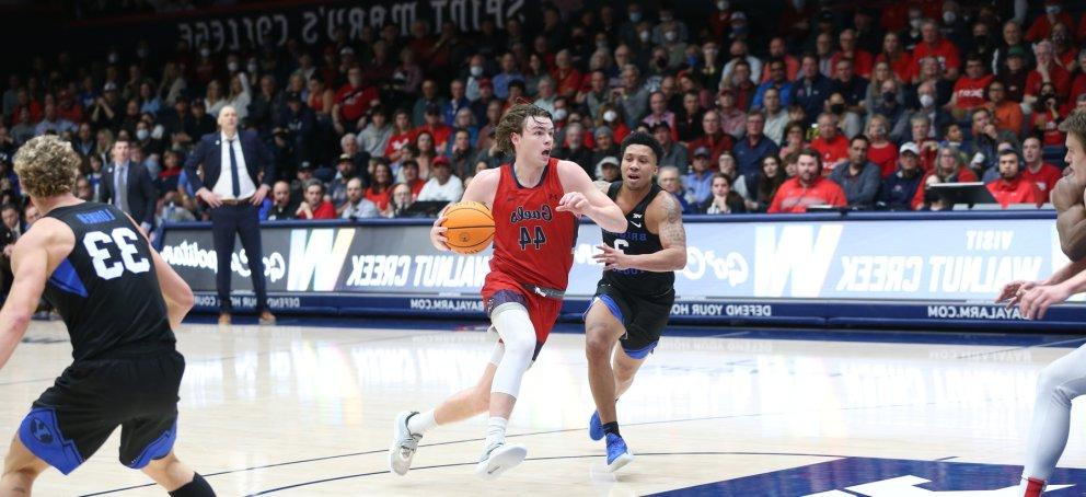 A Saint Mary's basketball player dribbling the ball surrounded by the opposing team. 